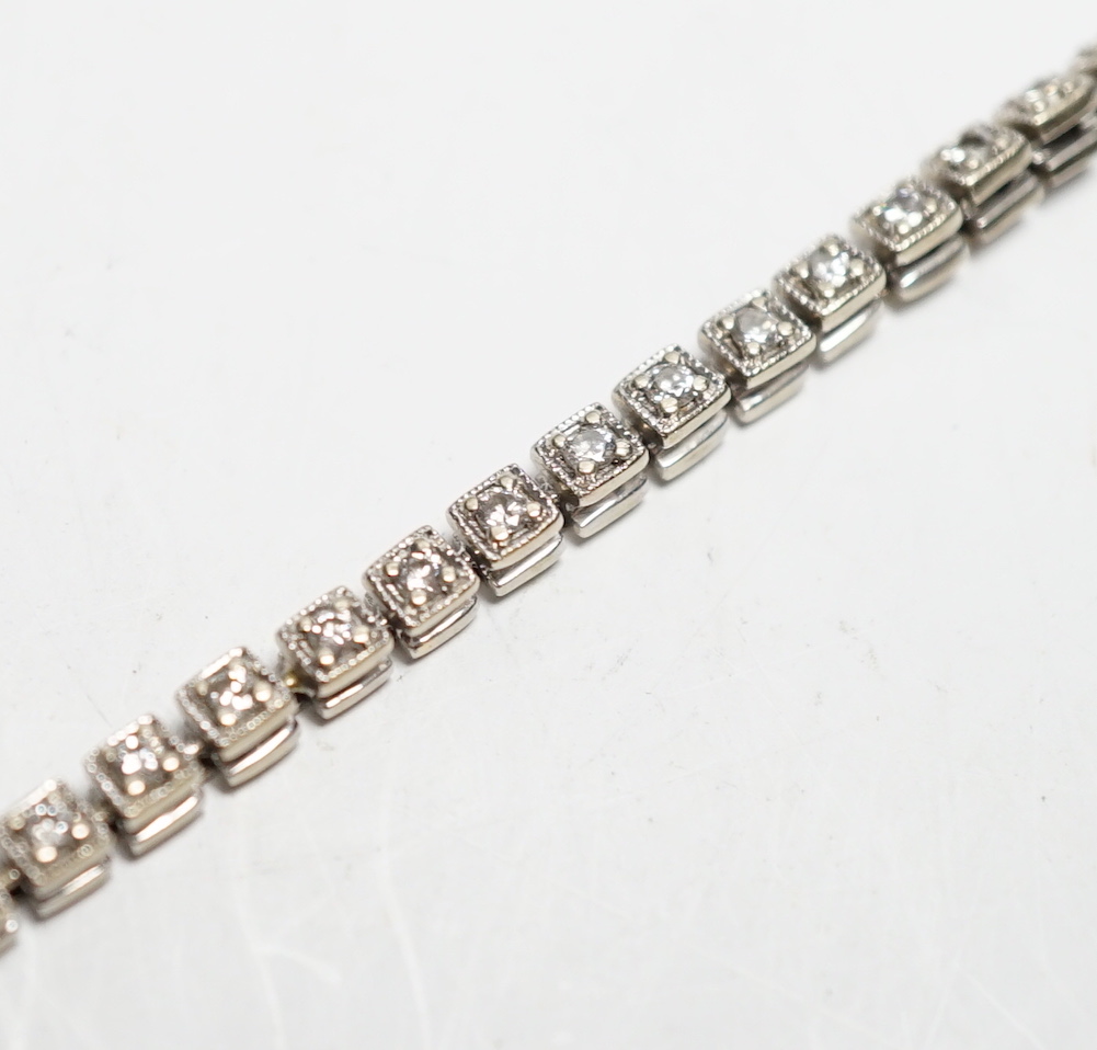 A 750 white metal and diamond line bracelet, set with sixty small stones, 20.8cm, gross weight 12 grams.